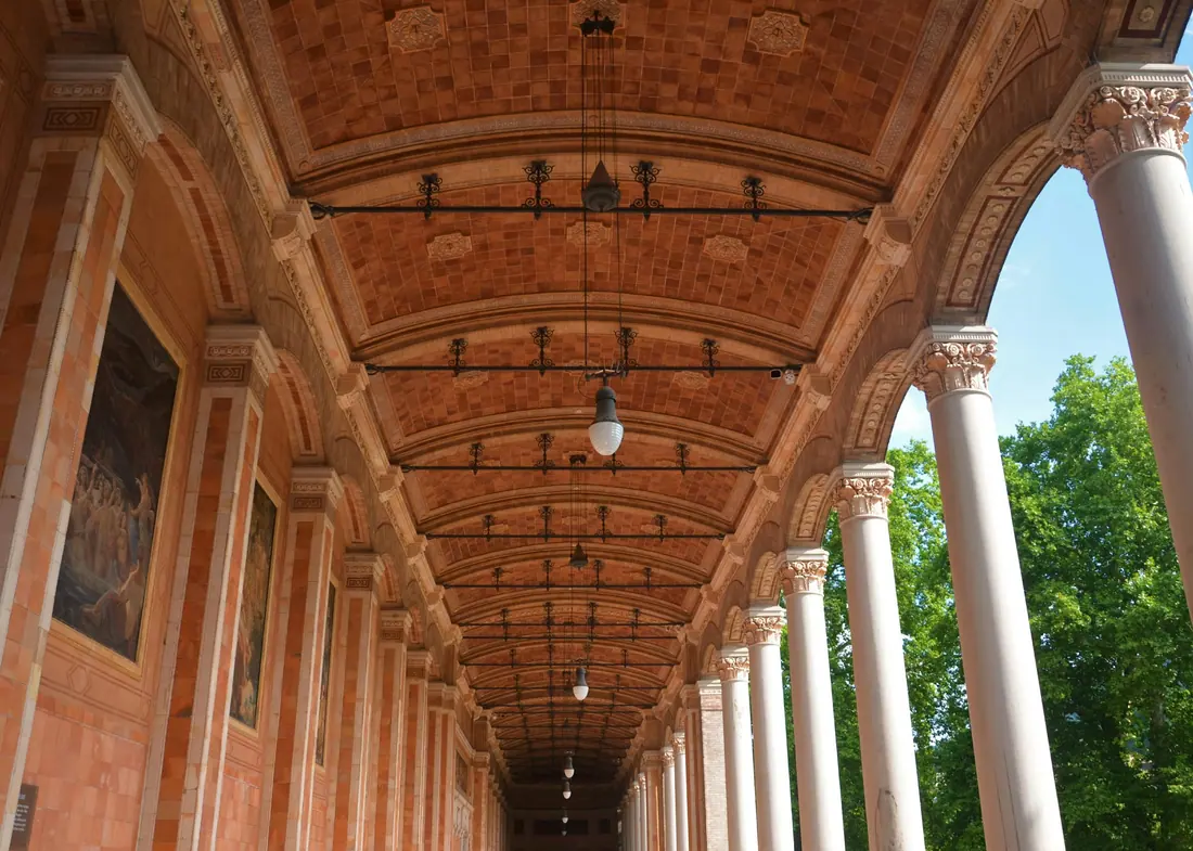 A colonnaded arcade in Baden-Baden with a painted timber ceiling and a row of slender columns
