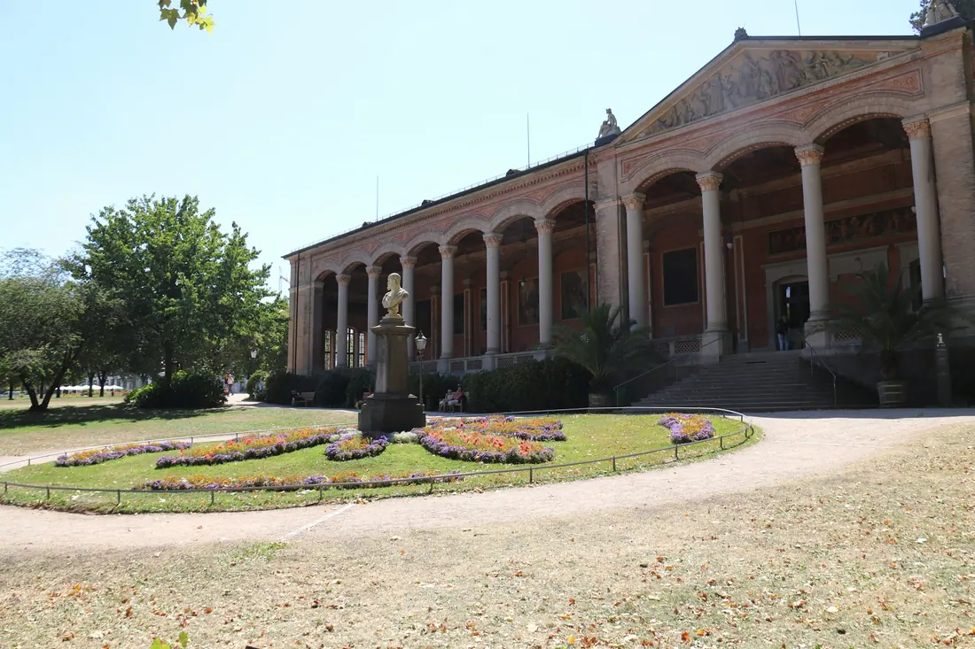A long arcaded building behind a flower bed in a park in Baden-Baden