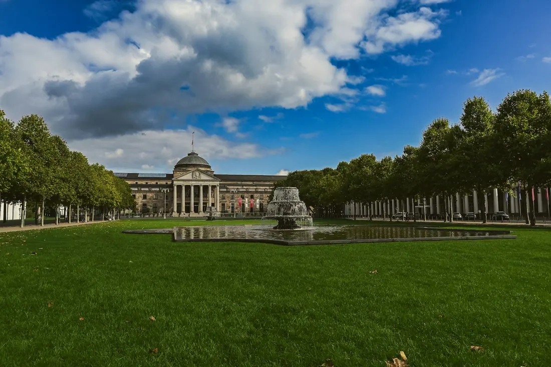 The Kurhaus in Wiesbaden seen across the lawn and fountain under a blue sky with clouds